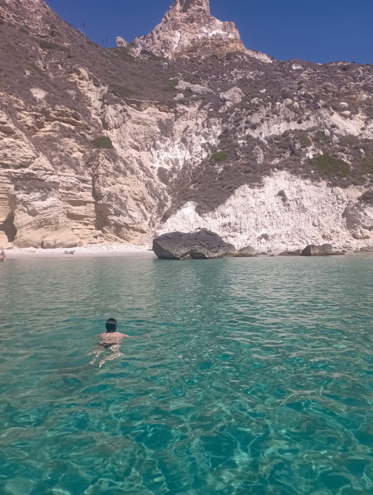 Person swimming in crystal clear water at Devil’s Saddle in Cagliari
