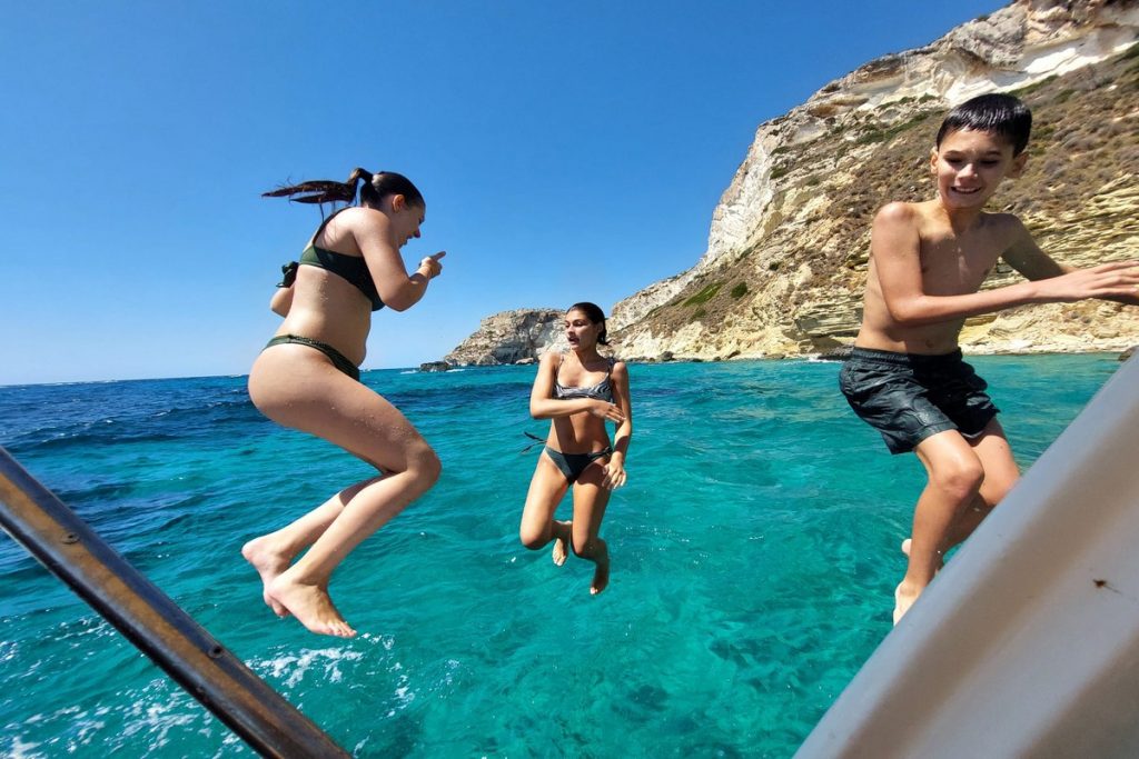 People swimming in crystal-clear waters during a private boat tour in Cagliari at Devil’s Saddle